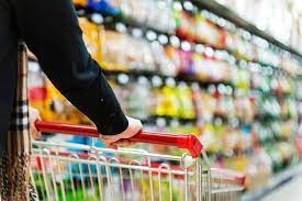 Image showing a shopper in a grocery store with the background of shelves filled with products, symbolizing consumer behavior. This accompanies the news of the US Consumer Confidence Index falling 7.2 points to 92.9 in March, with both the Present Situation Index and Expectations Index showing declines.